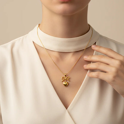 Gold necklace with a bow pendant worn by a person in a white outfit.