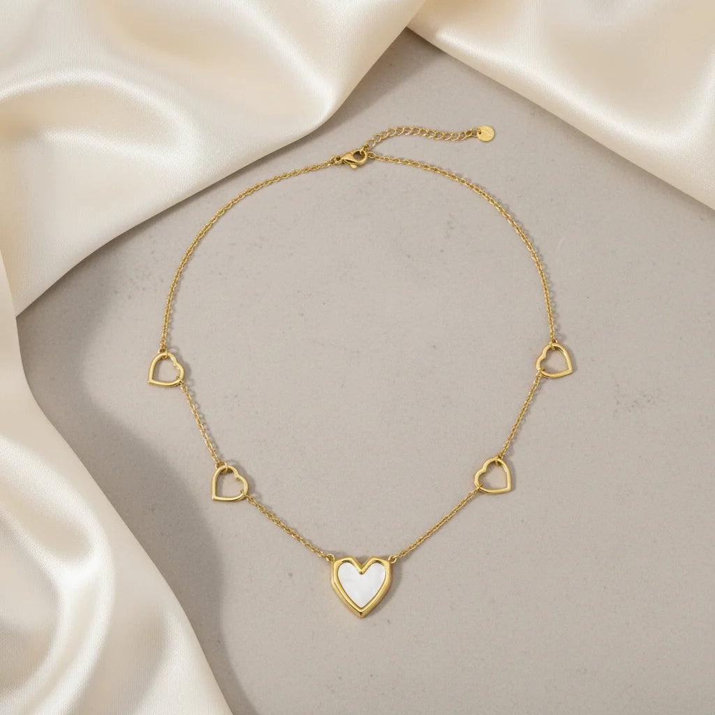 Gold necklace with heart-shaped pendants on a beige fabric background
