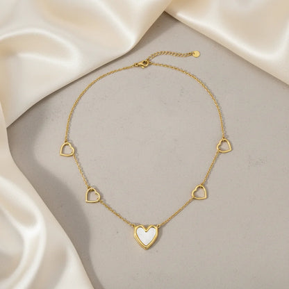 Gold necklace with heart-shaped pendants on a beige fabric background