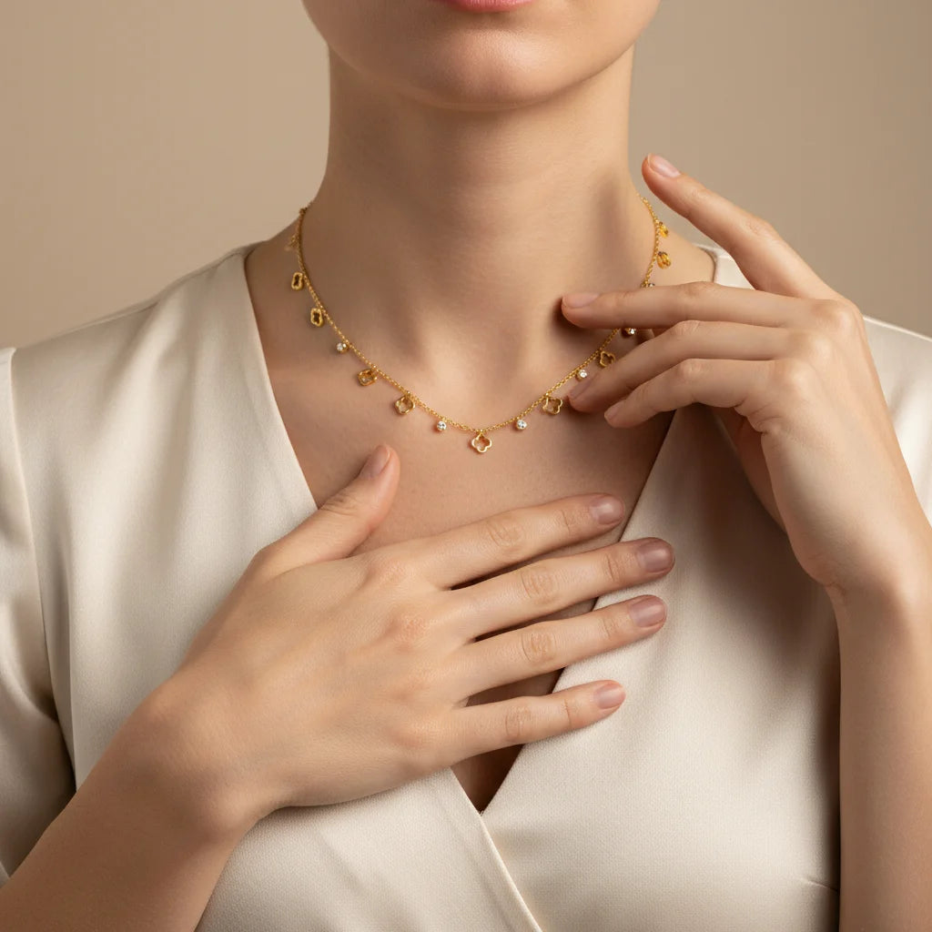 Gold necklace being worn by a person with hands adjusting it against a neutral background