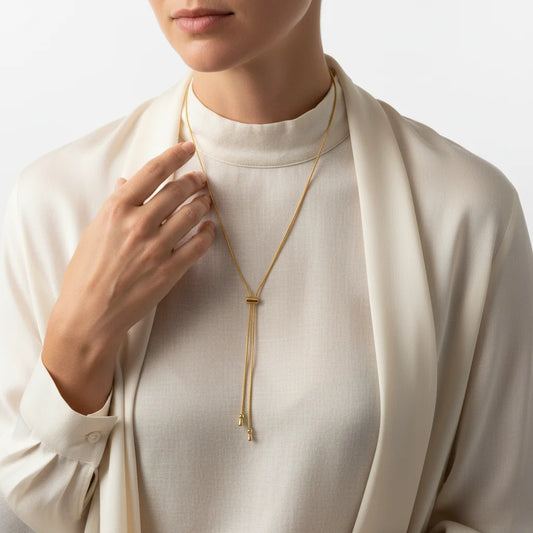 Person wearing a gold necklace with a plain background