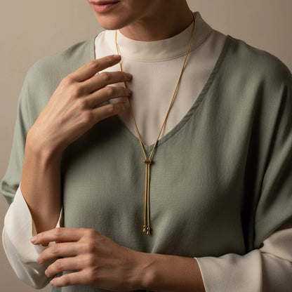 Person wearing a gold necklace with a neutral background