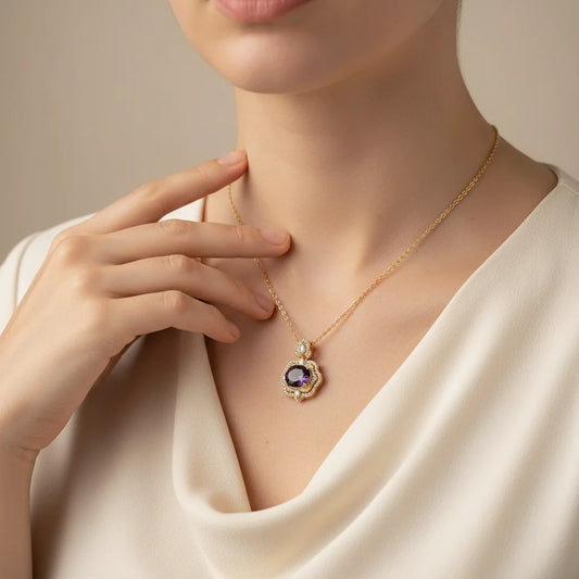 Gold necklace with a purple gemstone worn by a person against a neutral background