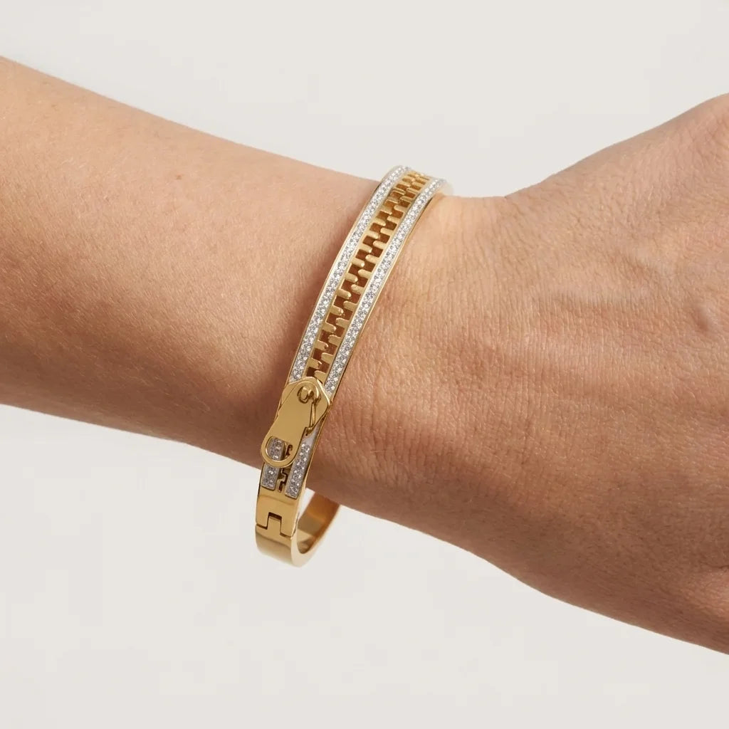 Gold bracelet with diamond accents on a wrist against a light background
