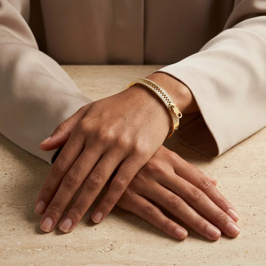 Close-up of hands wearing a gold bracelet on a beige surface