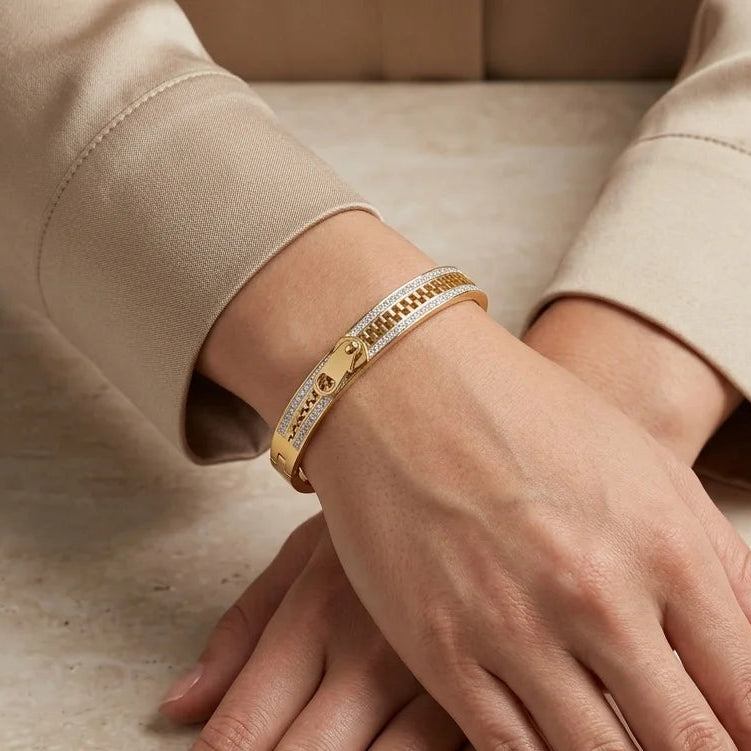 Close-up of hands wearing gold bracelets on a neutral background