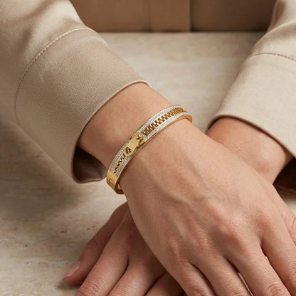 Close-up of hands wearing gold bracelets on a neutral background