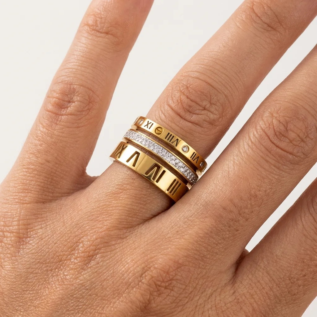 Gold ring with Roman numeral design on a hand against a white background