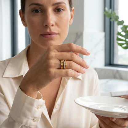 Woman wearing gold rings holding a white plate indoors