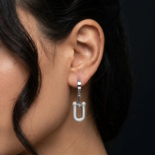 Close-up of an ear wearing a silver hoop earring with a dark background
