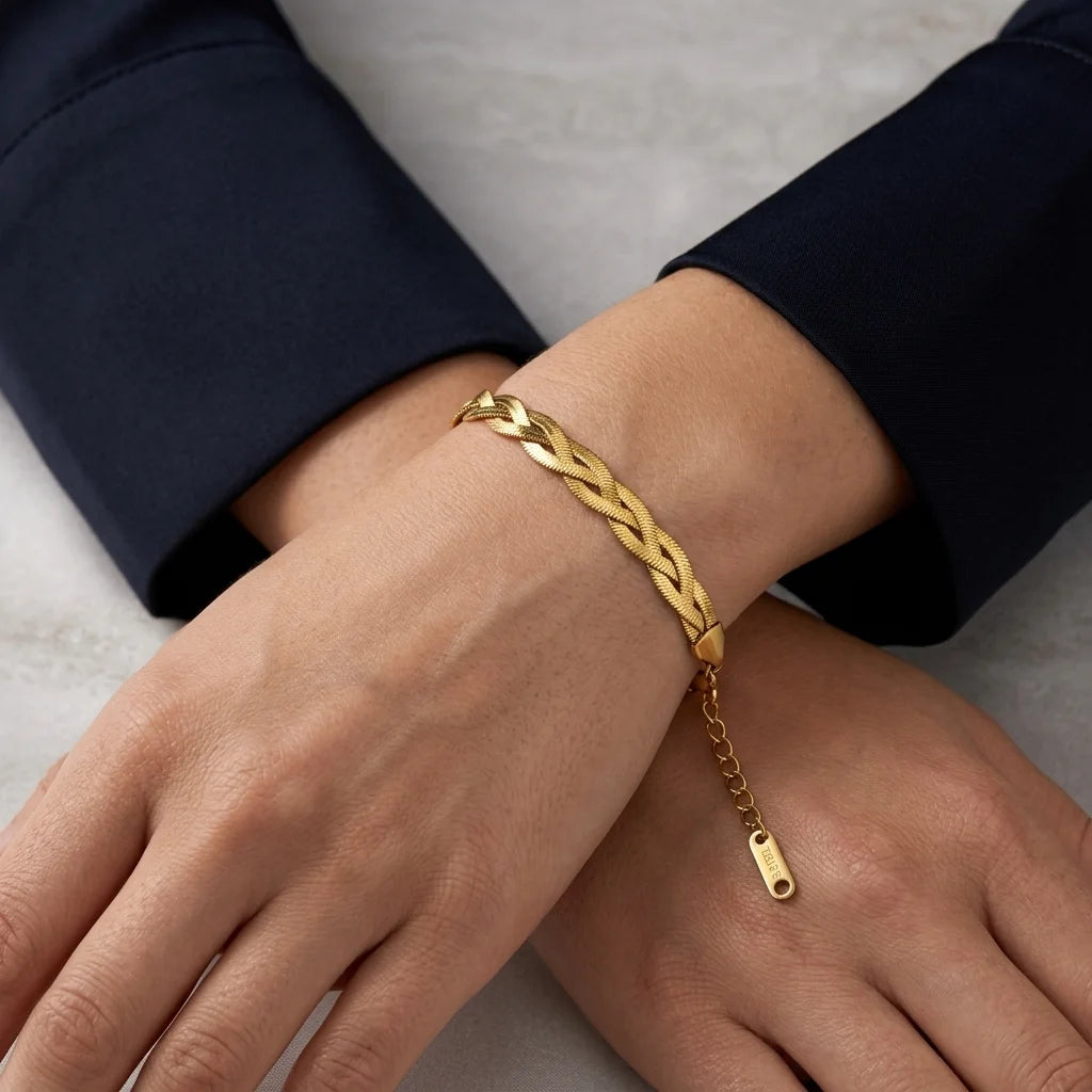 Gold bracelet on a person's wrist with a neutral background