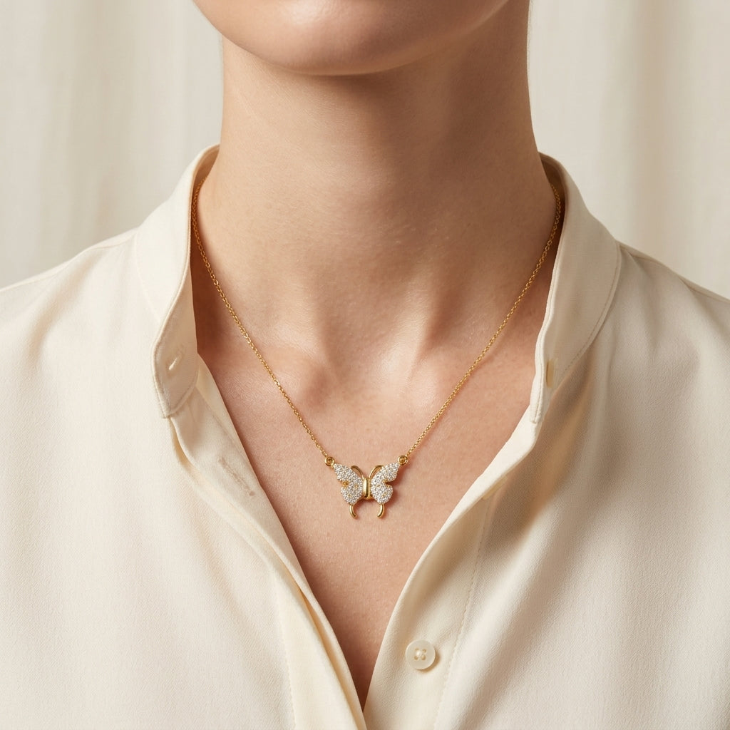 Gold butterfly necklace worn by a person in a cream shirt