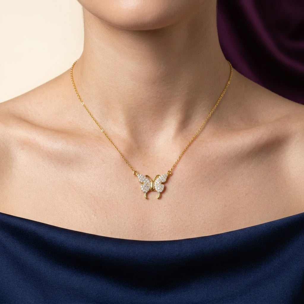 Gold butterfly necklace with diamonds on a person wearing a dark blue garment.