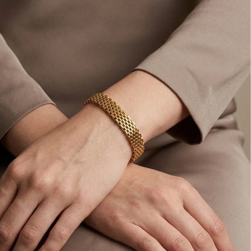 Close-up of hands with a gold bracelet on a neutral background