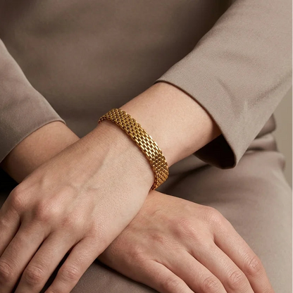 Close-up of hands with a gold bracelet on a neutral background