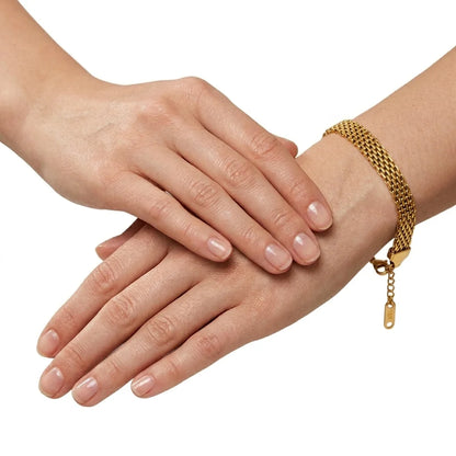 Close-up of hands with a gold bracelet on a white background