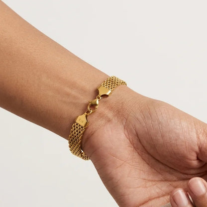 Gold bracelet on a wrist with a neutral background