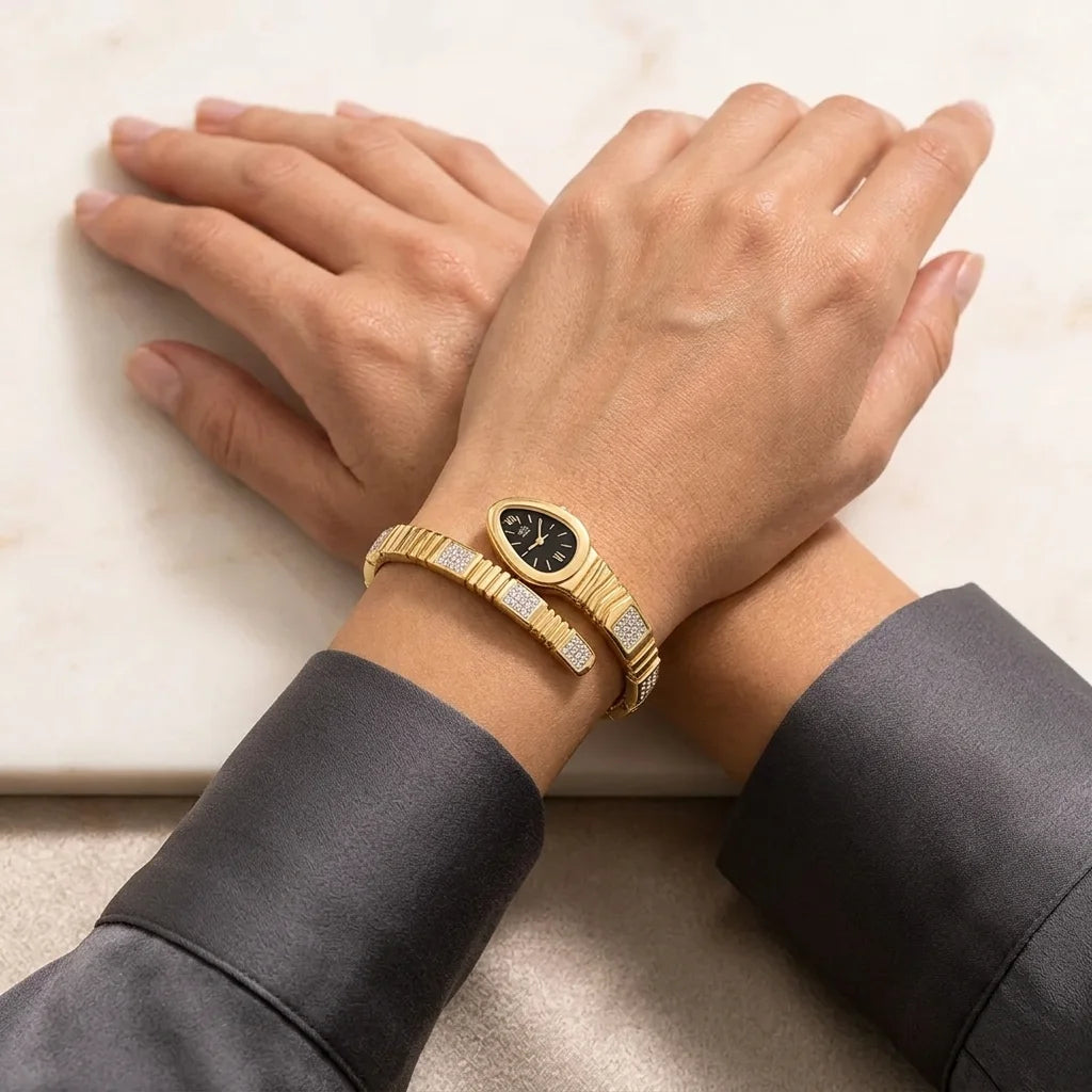 Gold bracelet with a watch face on a wrist against a neutral background