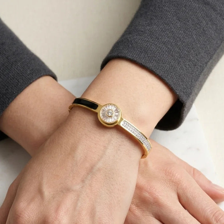 Gold bracelet with a diamond on a person's wrist against a neutral background