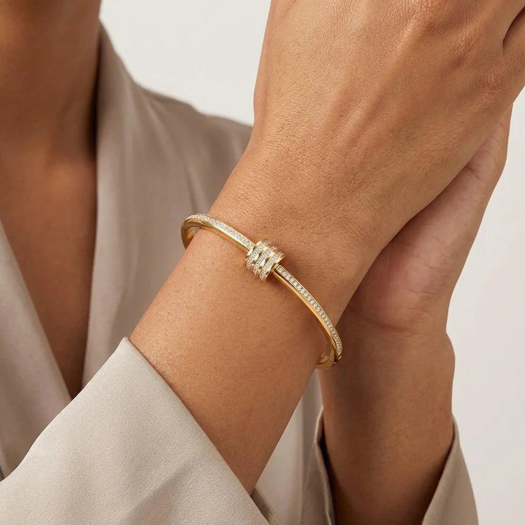 Gold bracelet on a wrist with a neutral background