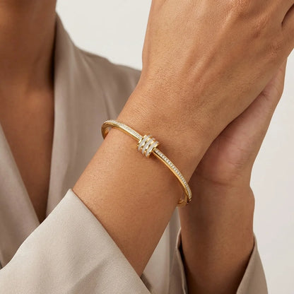 Gold bracelet on a wrist with a neutral background