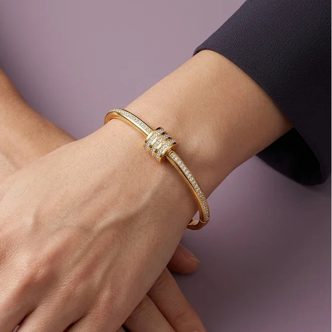 Gold bracelet on a person's wrist with a plain background