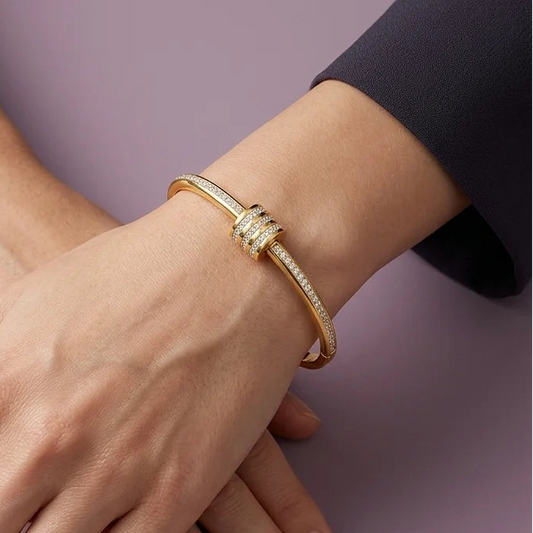 Gold bracelet on a person's wrist with a plain background