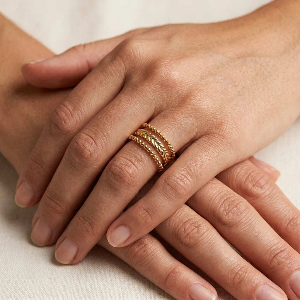 Close-up of hands with a gold ring on a neutral background
