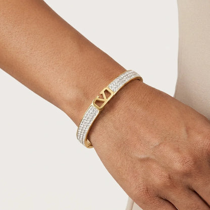 Gold bracelet with diamond accents on a wrist against a neutral background