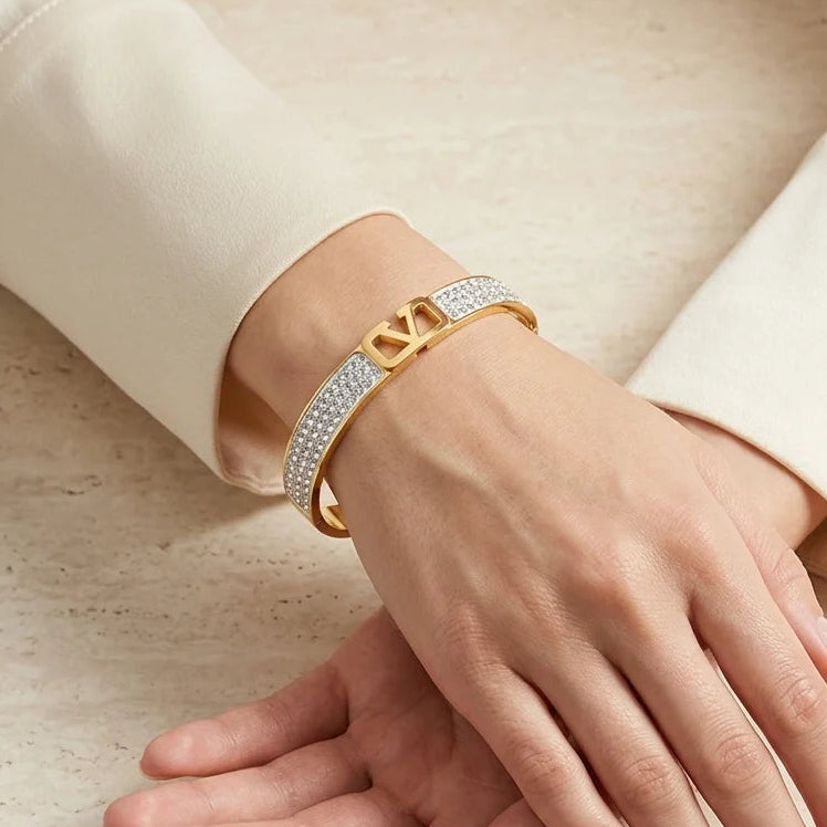 Gold bracelet on a hand with a neutral background