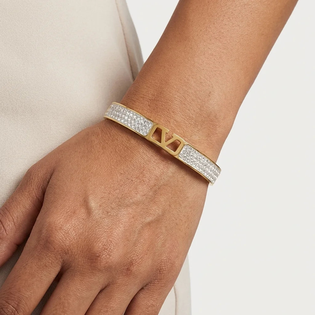 Gold and diamond bracelet on a wrist against a neutral background