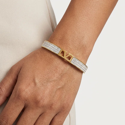Gold and diamond bracelet on a wrist against a neutral background