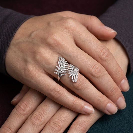 Hand wearing a silver leaf-shaped ring with a dark background