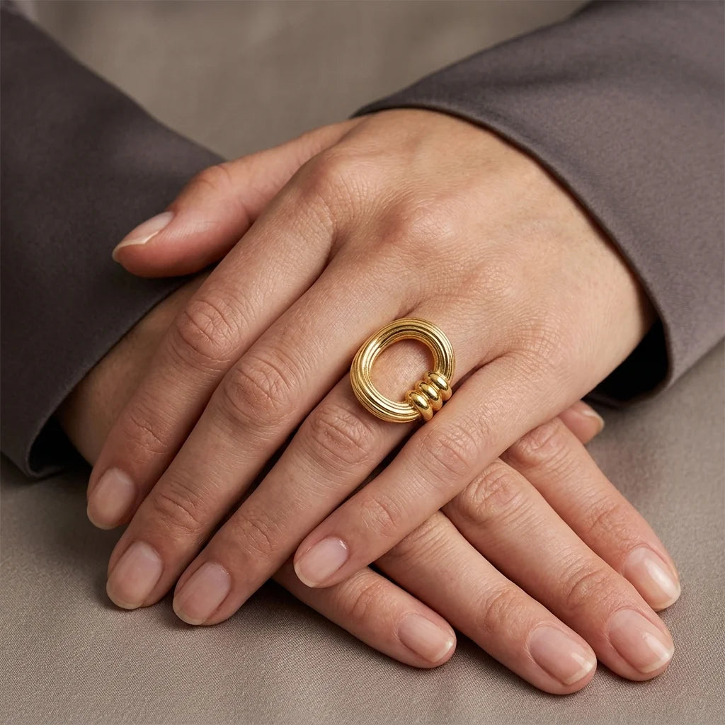 Gold ring on a hand with a neutral background