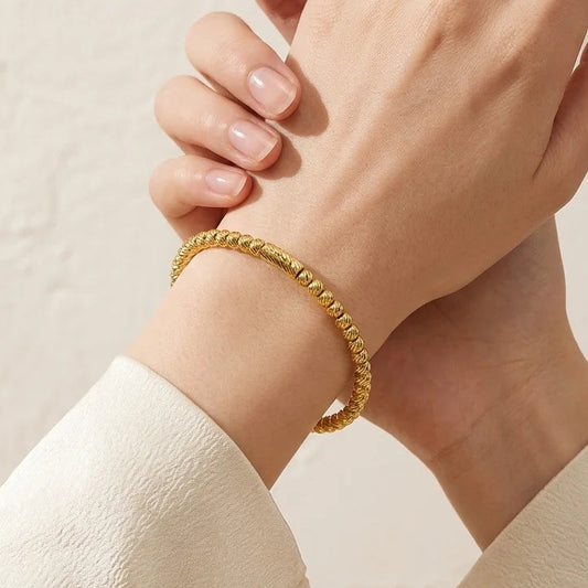 Gold bracelet on a hand against a beige background with 'Elegance Defined' text.