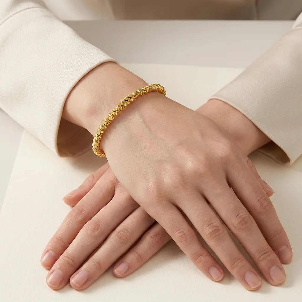 Gold bracelet on a person's wrist with a neutral background