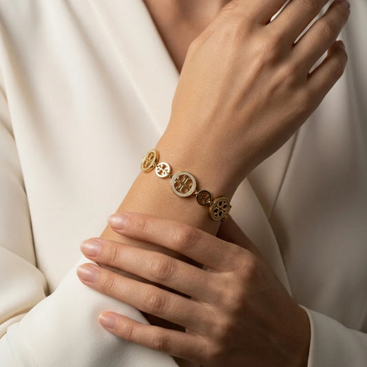 Gold bracelet on a wrist with a neutral background