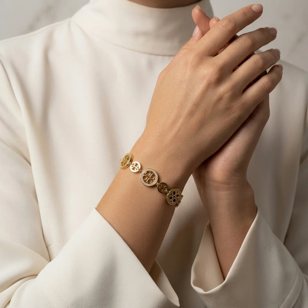 Gold bracelet on a person's wrist with a neutral background