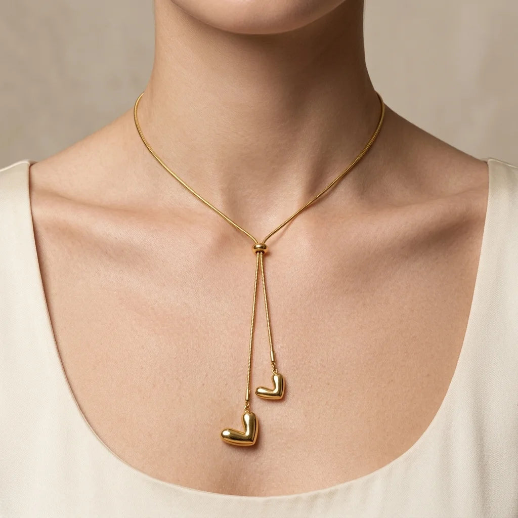 Gold necklace with heart-shaped pendants on a neutral background