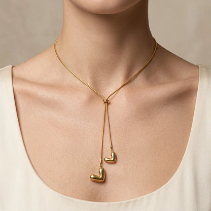 Gold necklace with heart-shaped pendants on a neutral background