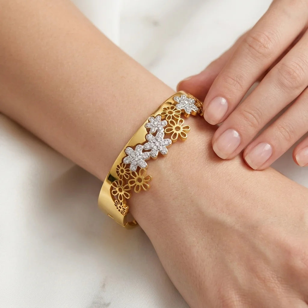 Gold bracelet with floral design on a wrist against a white background