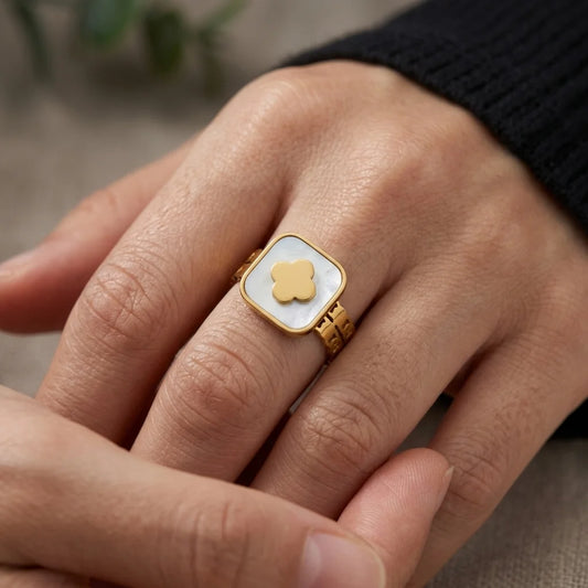 Gold ring with a white stone and gold heart on a person's finger