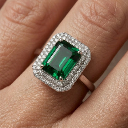 Green gemstone ring with silver frame on a finger
