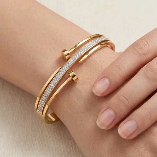 Gold bracelet with diamond accents on a wrist against a beige background