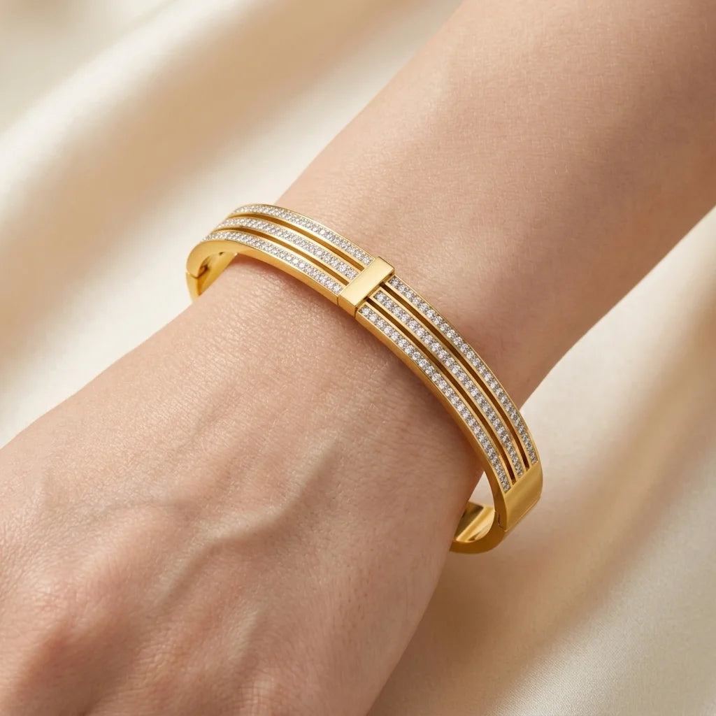 Gold bracelet with diamond accents on a wrist against a beige background