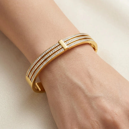 Gold bracelet with diamonds on a wrist against a neutral background