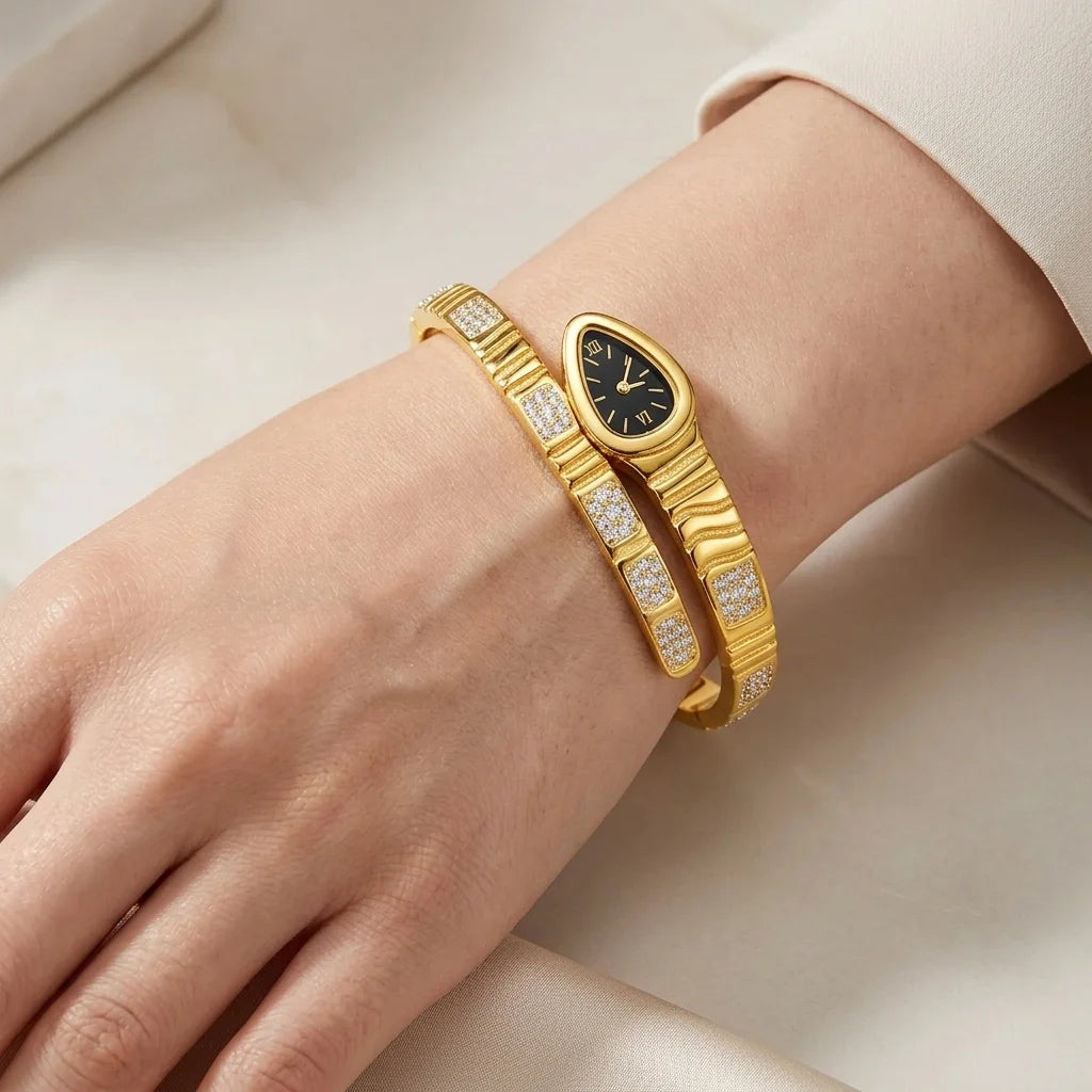 Gold bracelet with a watch face on a wrist against a neutral background