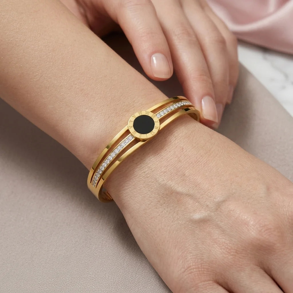 Gold bracelet with a black center stone on a wrist against a neutral background