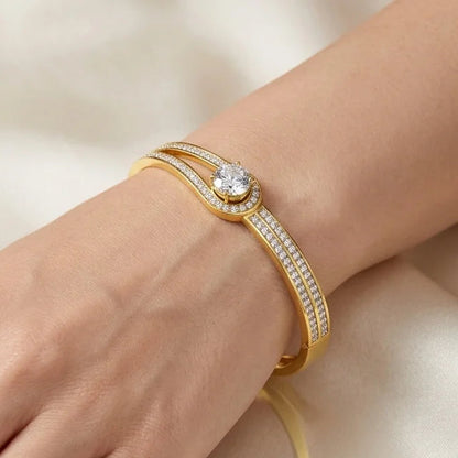 Gold bracelet with a diamond on a hand against a beige background