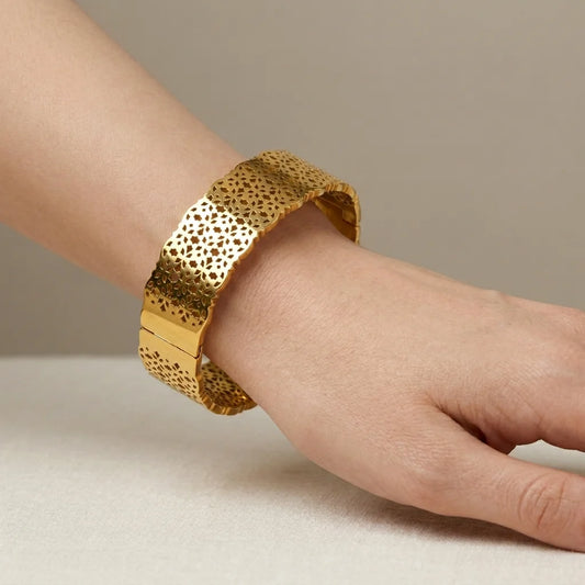 Gold bracelet on a wrist against a neutral background
